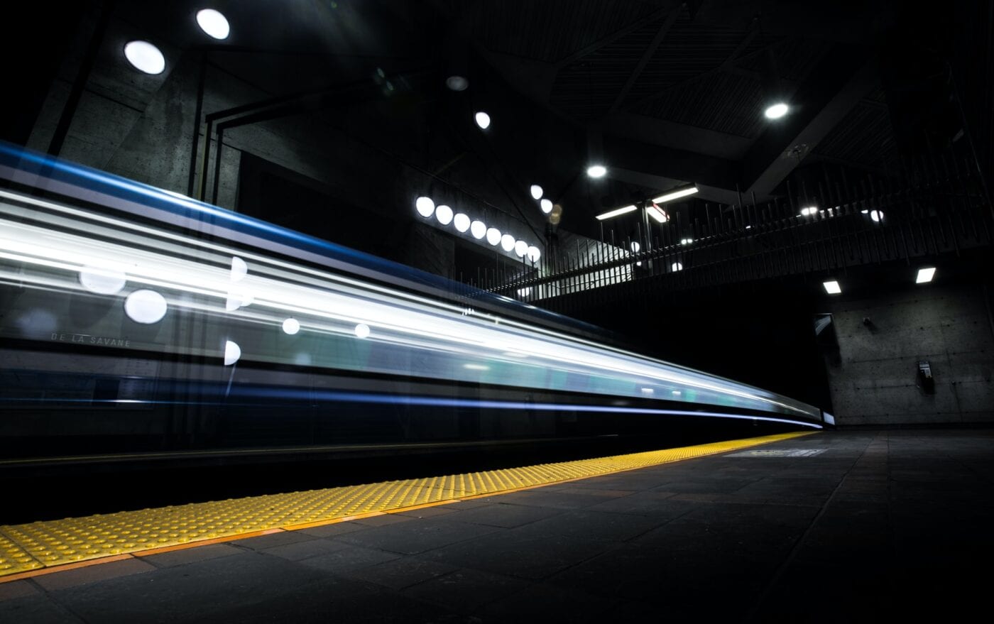 Blurred motion of a subway train speeding through an underground station at night